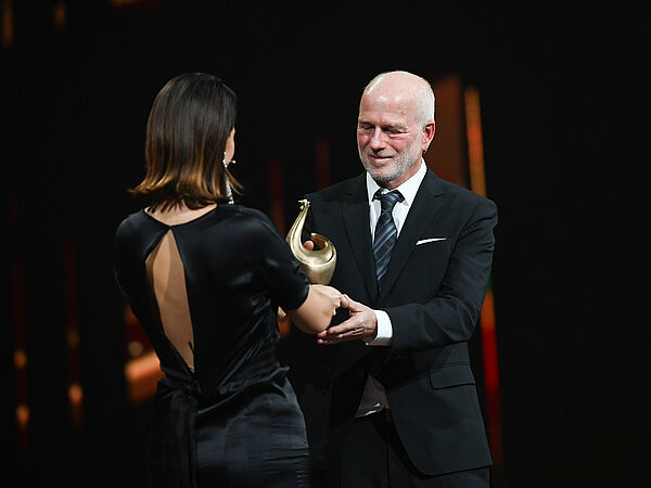 Yara Hoffmann überreicht Peter Nitschke eine Goldene Henne.