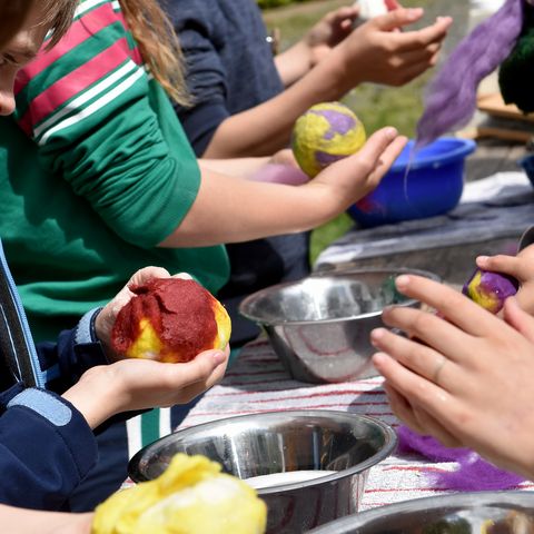 Kinder reiben Wollbälle mit Seifenwasser ein