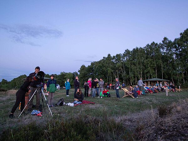 Sternenwanderung Auf einem Hügel treffen sich etwa 40 Menschen um in der Abenddämmerungen Sterne zu beobachten. Es wurde ein großes Teleskop aufgebaut.