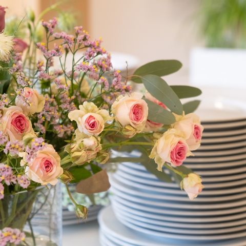 Blumenstrauß in rose vor Tellerstapel