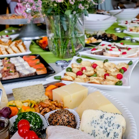 Buffet mit Käseplatte und Schnittchenplatten und Blumen in Vase in der Mitte