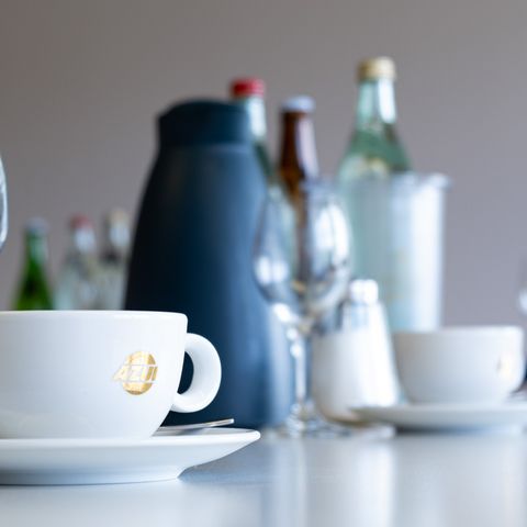 Gläser, Tassen, Kaffeekanne und Flaschen auf Konferenztisch 