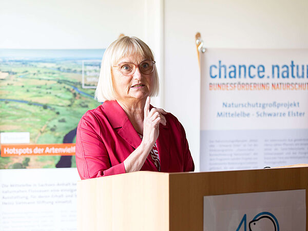 Dr. Bettina Hoffmann: Parlamentarische Staatssekretärin bei der Bundesministerin für Umwelt, Naturschutz, nukleare Sicherheit und Verbraucherschutz. Staatssekretärin Dr. Bettina Hoffmann am Rednerpult. Hinter ihr befinden sich Banner der Heinz Sielmann Stiftung Stiftung und des Förderprogramms chance.natur.