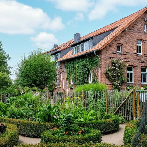 Blick über den grünen Bauerngarten auf Gut Herbigshagen mit Hofgebäude im Hintergrund