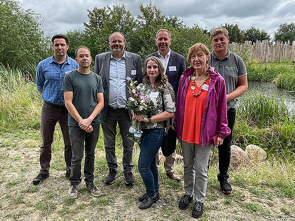 Gruppenfoto mit sieben Personen vor einem naturnahen Teich.