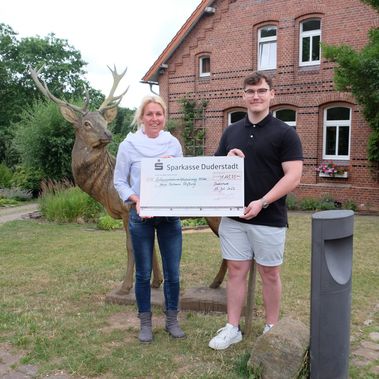 Ilia Friesen übergibt den symbolischen Scheck an Julia Hagemann.