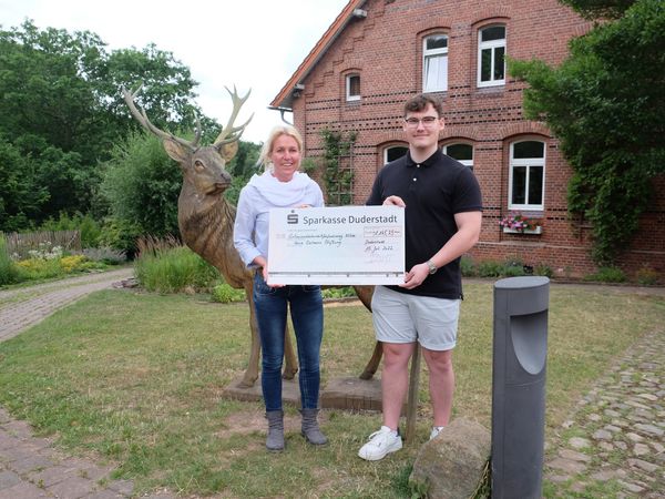 Ilia Friesen übergibt den symbolischen Scheck an Julia Hagemann.