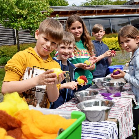 Kinder beim Wollfilzen vor der Dachsburg schauen in die Kamera